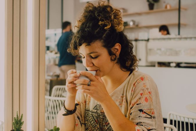 Positive woman drinking coffee in cafe