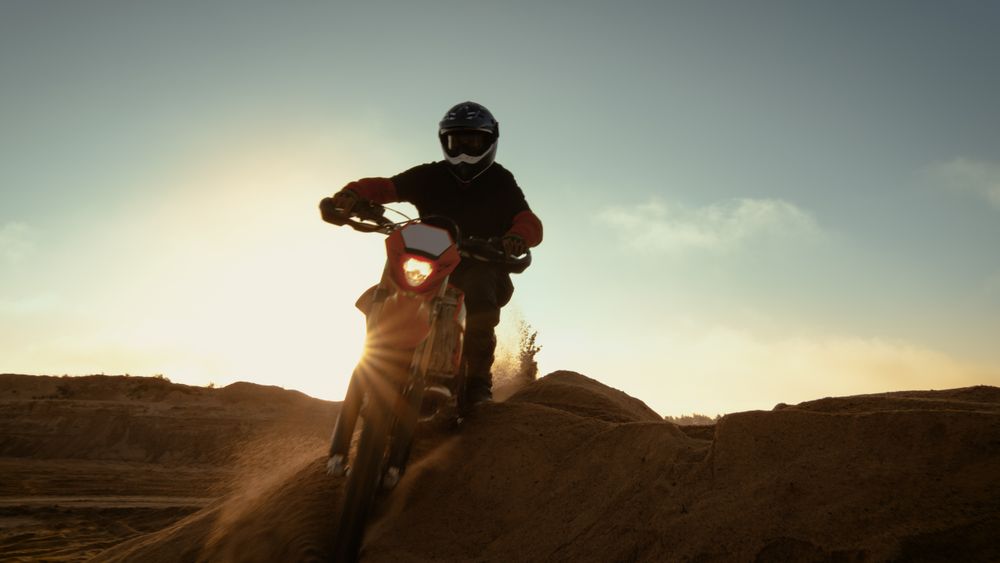 Professional Motocross Motorcycle Rider Driving Over the Dune and Further Down the Off-Road Track.