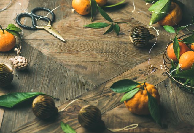 Freshly picked tangerines with leaves on wooden table, with Christmas decorations, copy space