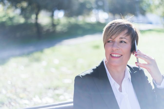 Businesswoman sitting in park with cellphone to ear