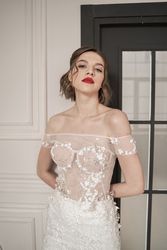 Magnificent pensive young bride in white lace dress looking at camera and pondering