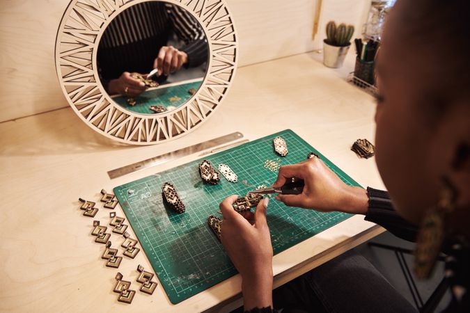 Black jewelry designing working with pliers in front of a mirror