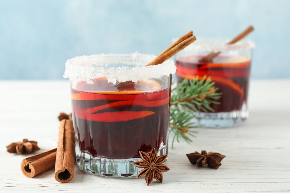 Glasses of tasty mulled wine on blue wooden background, space for text