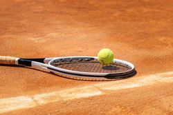 Tennis racket and ball on a dirt court