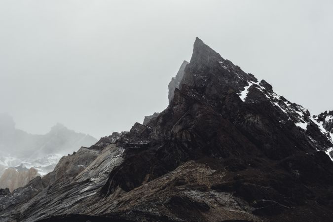 Harsh mountain snowy peak shrouded in fog
