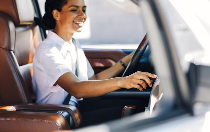 Side view of female smiling and holding a steering wheel