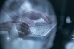 Doctor working at computer keyboard through X-ray film