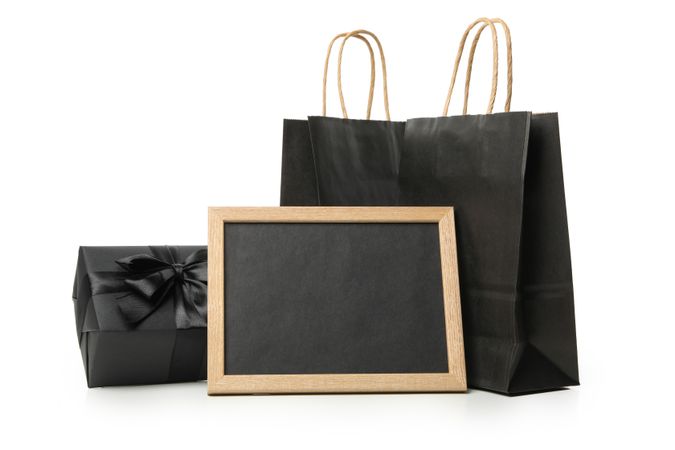 Paper bags, chalkboard and gift box isolated on bright background