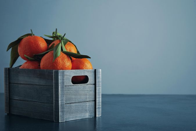 Crate of tangerines on light blue background
