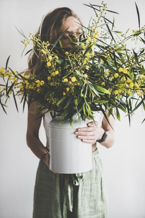 Woman holding mimosa branches in vase