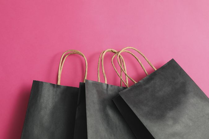 dark paper bags on pink background, space for text