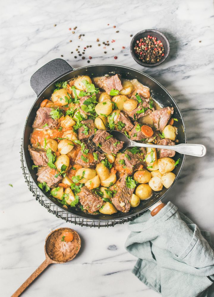 Braised beef stew with potatoes, carrots and parsley, with wooden spoon