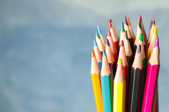 Multicolored pencils against light blue background, closeup