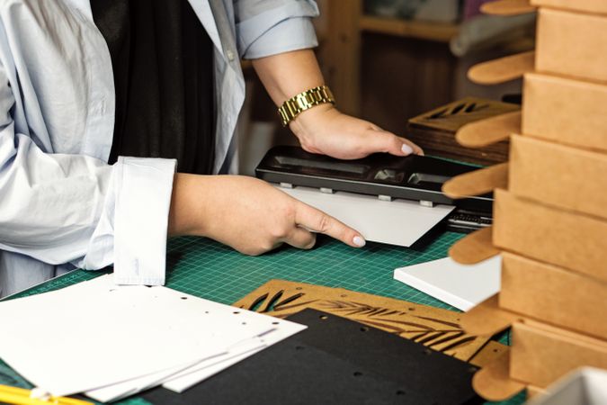 Female hands use hole punch to create perforations in removable paper blocks