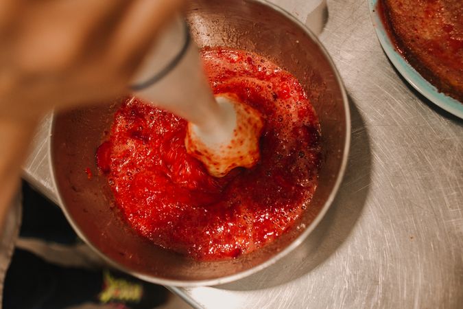 Berry smoothie making process on grey steel table