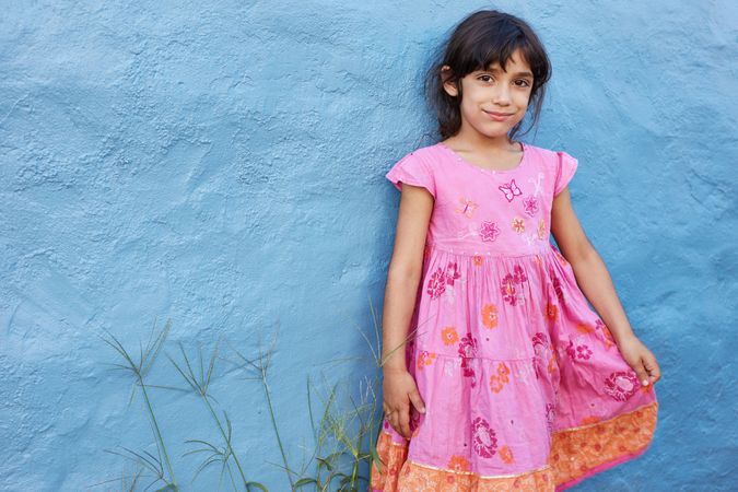 Shot of cute little girl in beautiful pink dress looking at camera