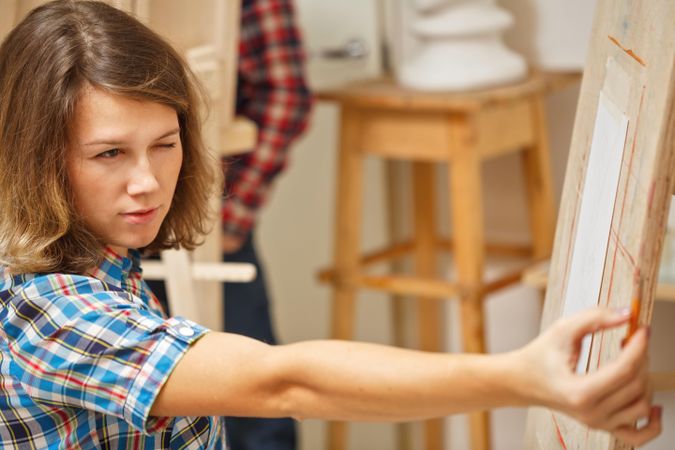 Woman using pencil to gauge proportion for painting