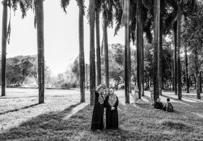 Grayscale photo of women wearing hijab taking selfie surrounded by trees