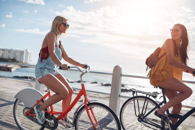 Two young women riding bicycles outdoors on a summer day
