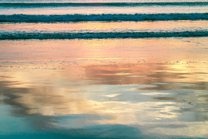 Seashore near waving water at sunset