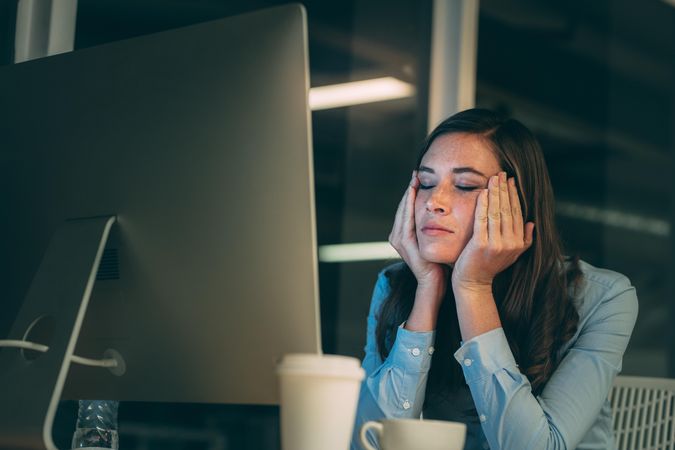 Businesswoman sitting in front of computer looking stressed out working late night in office
