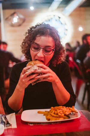 Young woman eating burger in cafe