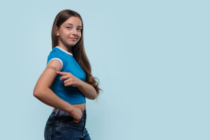 Young girl confidently pointing at bandage after vaccination
