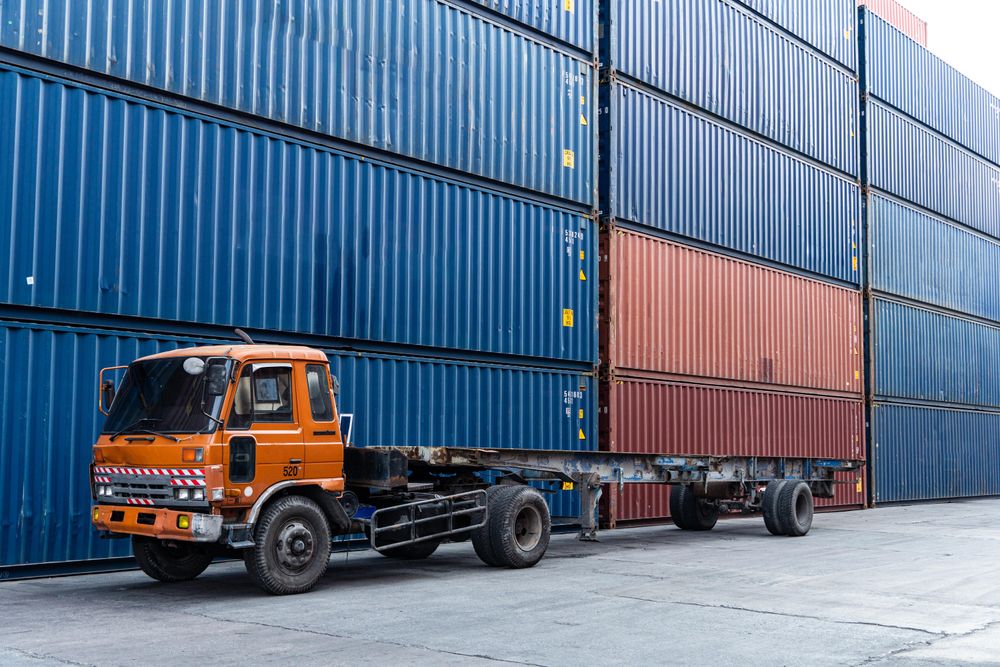 Truck at container warehouse preparing to lift cargo boxes