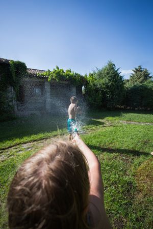 Little kids in swimwear having fun with splashing water