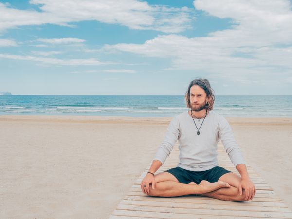 Man training yoga on beach