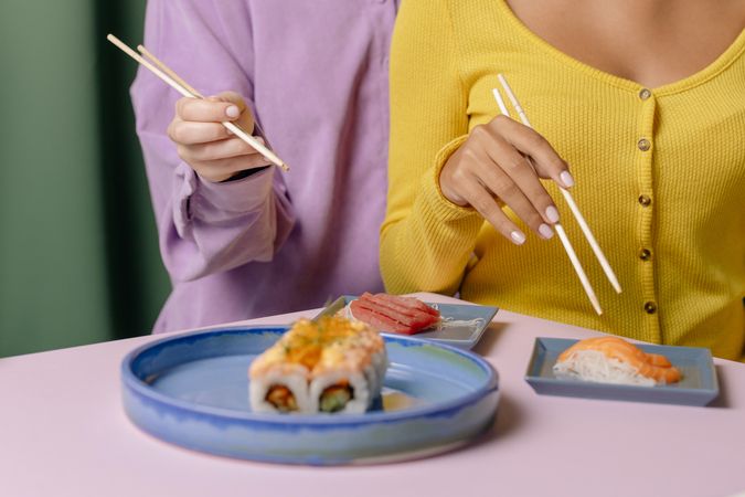 Cropped image of two women sitting beside each other eating sushi