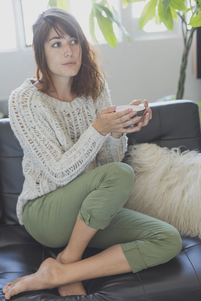 Calm female on cozy sofa with cup of tea