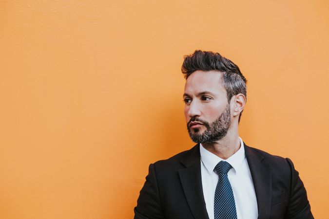 Adult stylish man in costume near orange wall