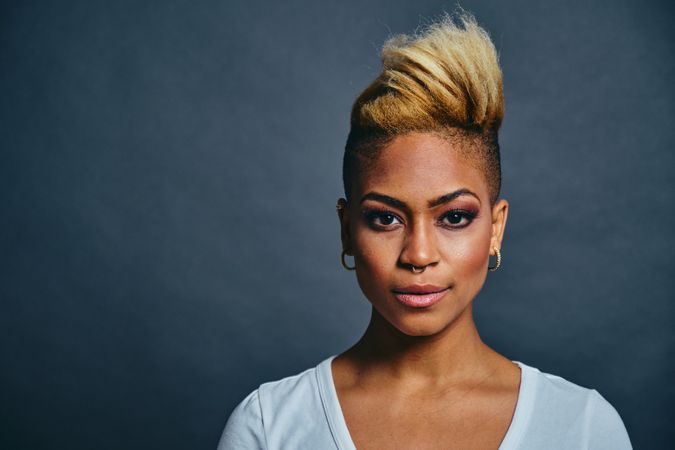 Portrait of Black woman with short blonde hair against gray background with copy space