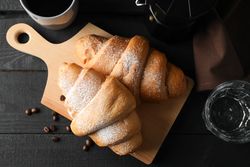 Composition with croissants on wooden breadboard, top view