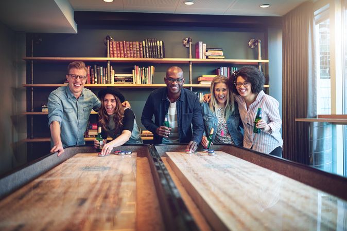 Multi-ethnic group of friends smiling while playing shuffleboard