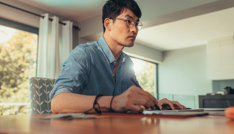 Side view of man working at home with graphic tablet