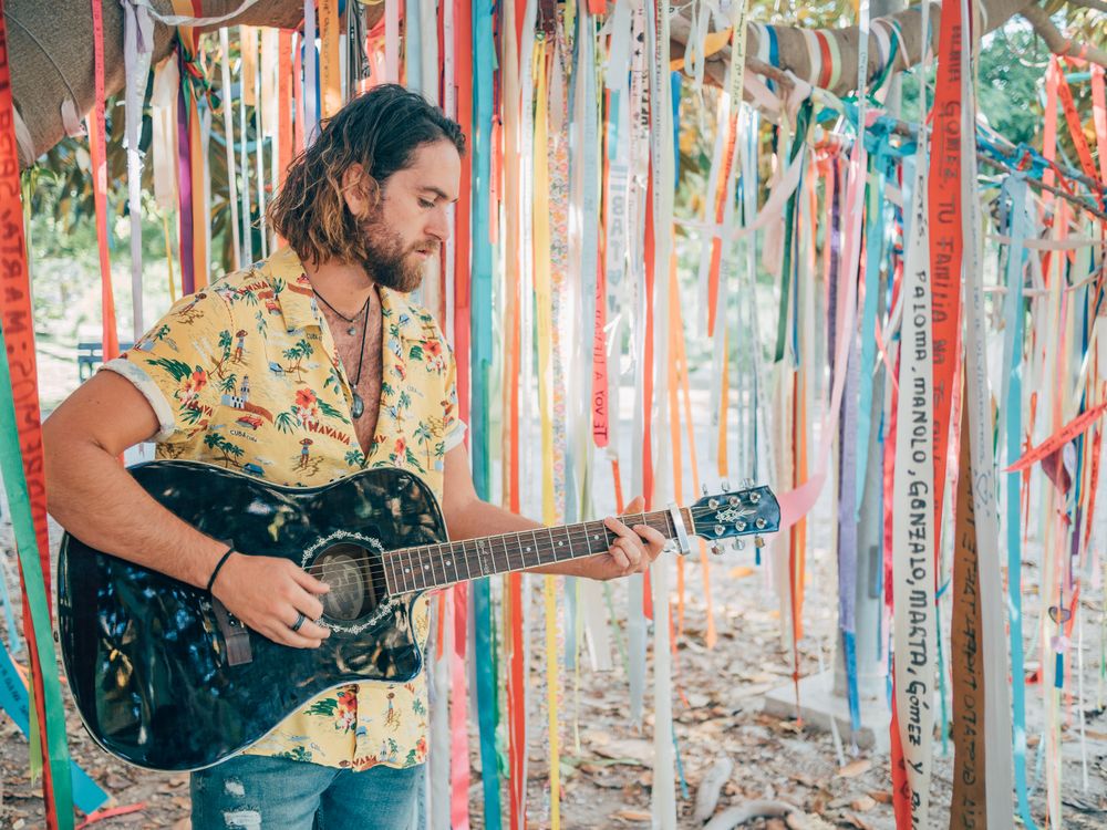 Man playing guitar under decorated tree