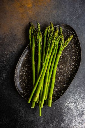 Loose raw asparagus on dark plate