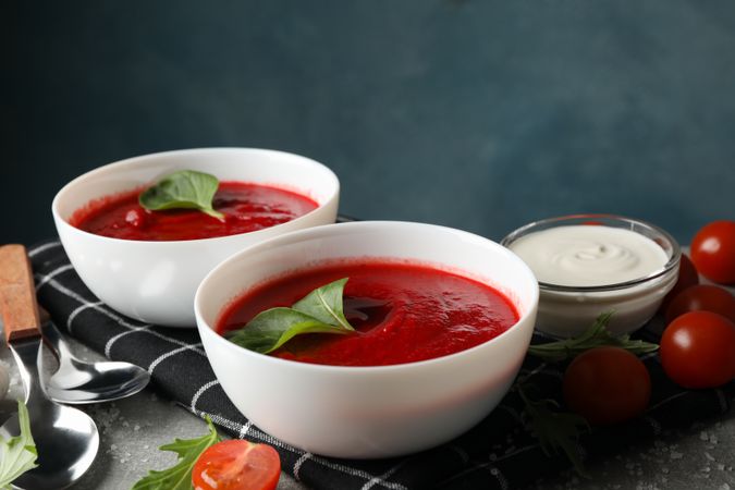 Tomato soup bowls surrounded by ingredients on grey kitchen counter
