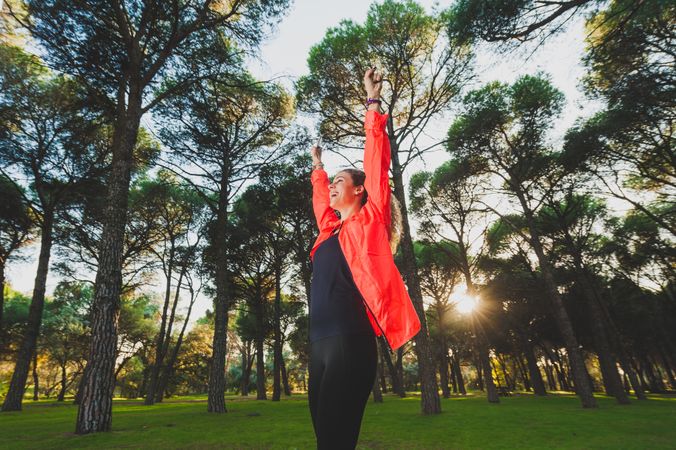 Excited sportswoman with arms raised in park