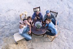 Aerial view of a group of friends sitting around a table holding beers
