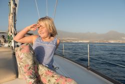 Smiling girl sitting on edge of yacht on water