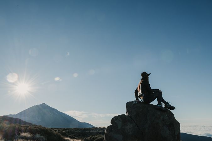 Woman sitting on rock in hillside