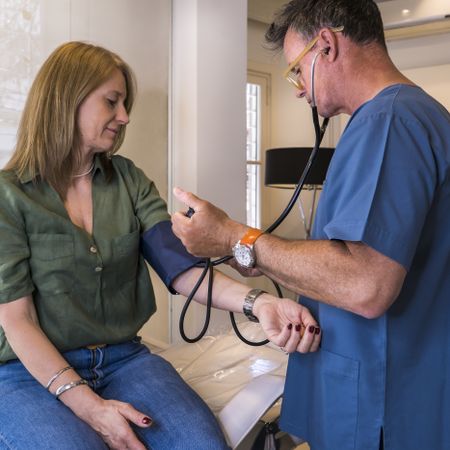 Male doctor is measuring blood pressure of male patient in hospital
