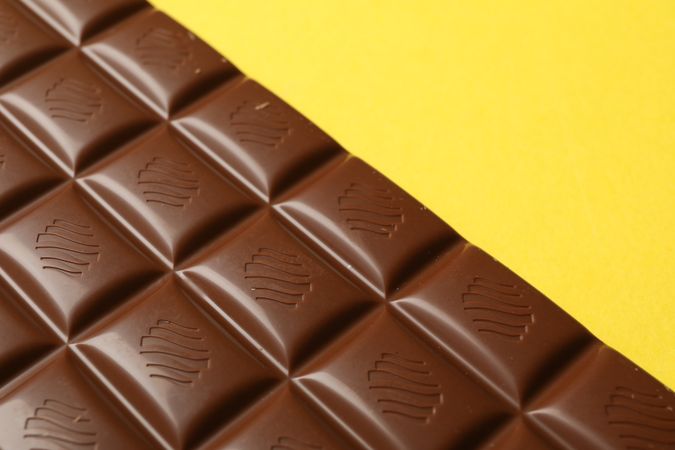 Tasty chocolate bar on yellow background. Sweet food