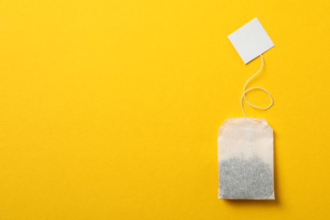 Tea bag with label on yellow background, space for text
