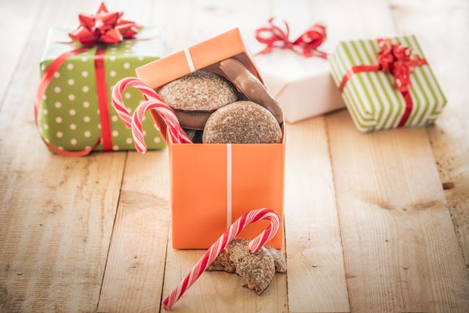 Gift box loaded with gingerbread next to three wrapped gifts