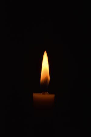 Side view of candle lit in the dark with copy space