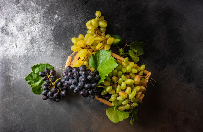 Top view of box of delicious fresh green & red grapes with leaves